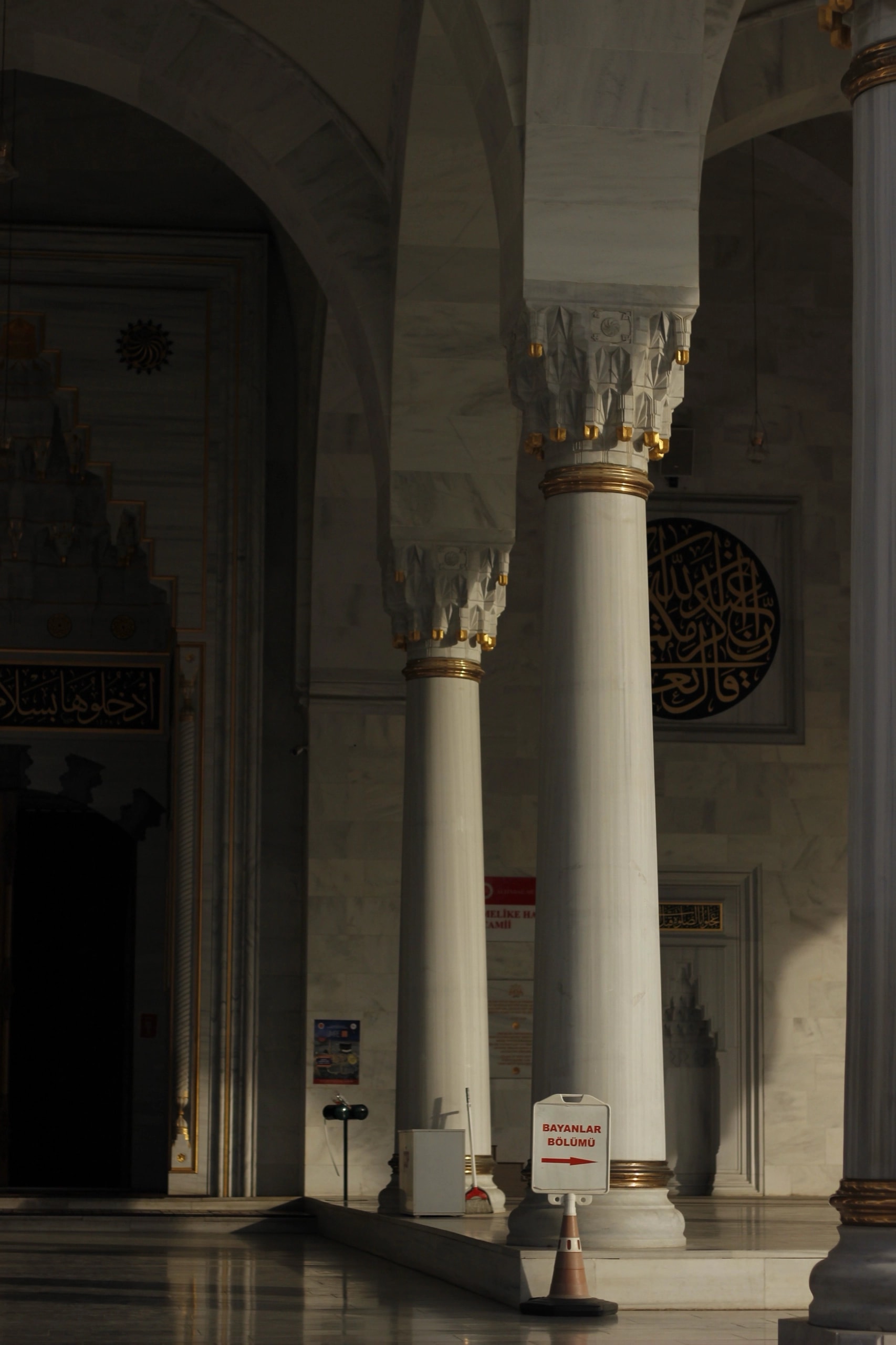 Marble columns and a calligraphy roundel in deep shadow